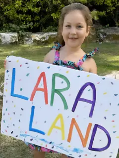Лара держит самодельную табличку «LARA LAND»